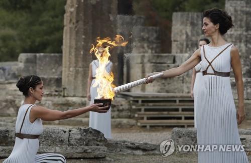 当地时间10月24日，扮演最高女祭司的希腊演员卡特里林娜·勒侯(右)点燃火种罐。(图片来源：韩联社)