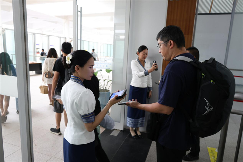 中老铁路首开早间磨丁至万象城际列车 列车员在车站核验车票。老中铁路有限公司供图